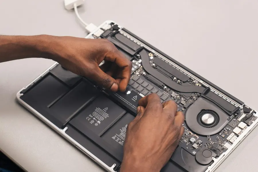 IT technician repairing a laptop during maintenance