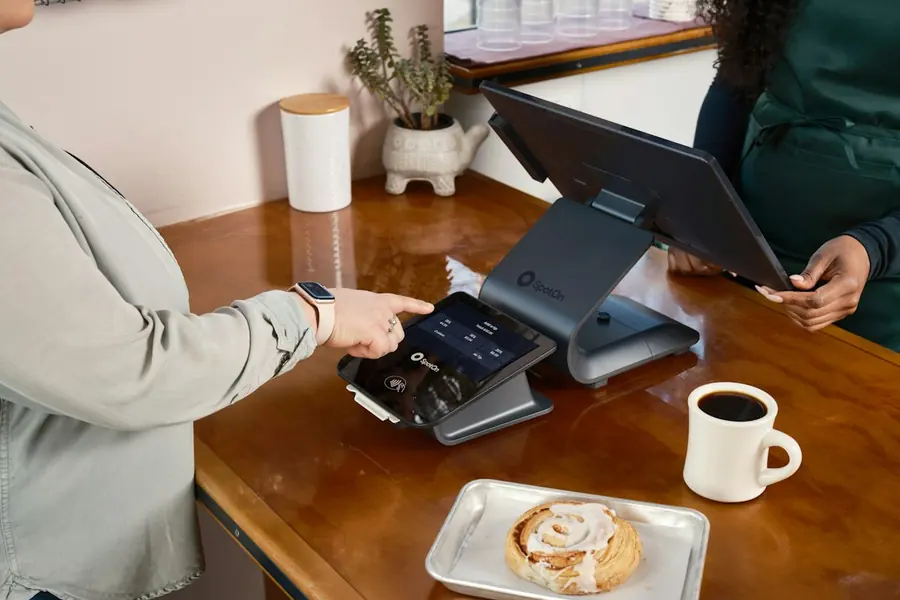 Customer paying by card at a POS terminal on a cafe counter